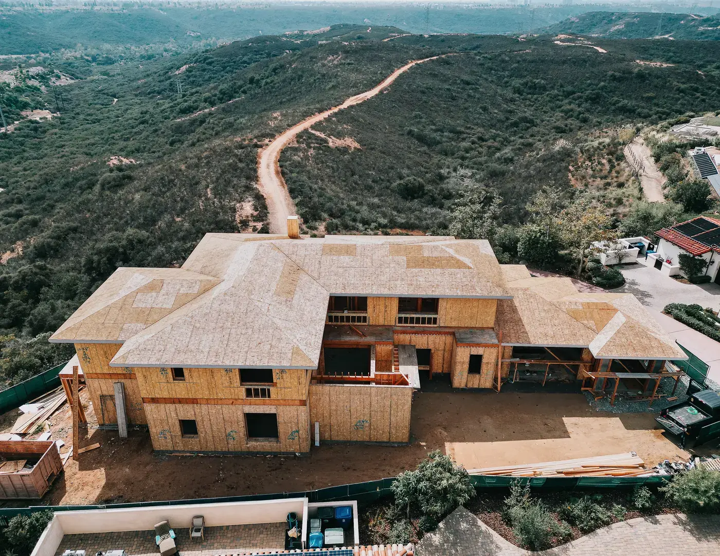 Drone photo of a residential framing job site with construction fencing and equipment staged